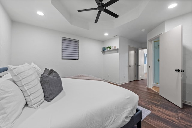 bedroom with dark hardwood / wood-style flooring, a raised ceiling, and ceiling fan