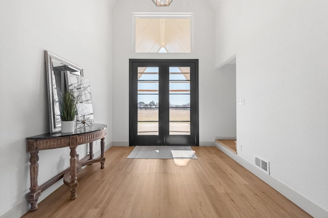 foyer entrance with light hardwood / wood-style floors, french doors, and a high ceiling