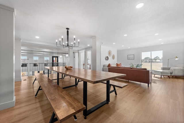 dining space with a chandelier, a textured ceiling, and light hardwood / wood-style floors