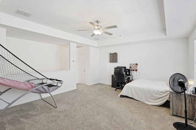 bedroom with ceiling fan, light colored carpet, and a tray ceiling