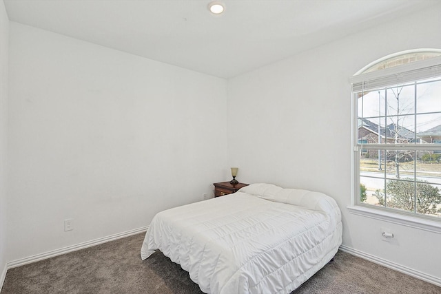 bedroom with multiple windows and dark carpet