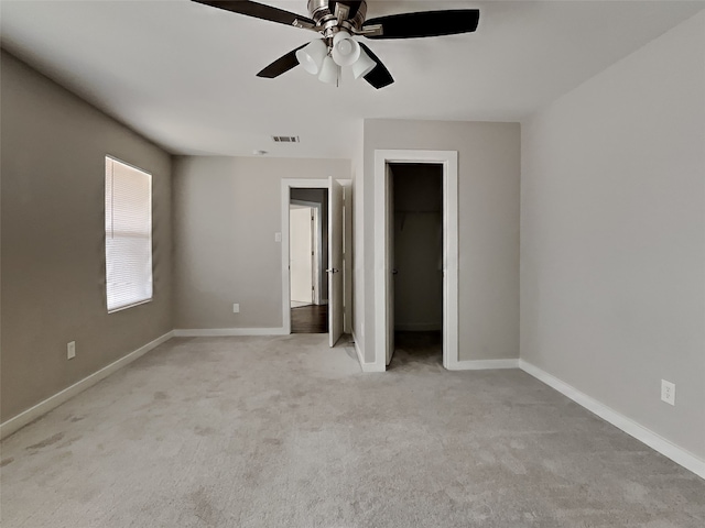 unfurnished bedroom with ceiling fan, light colored carpet, a spacious closet, and a closet