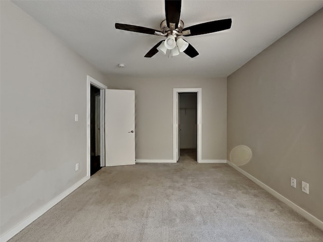 unfurnished bedroom featuring a spacious closet, light colored carpet, ceiling fan, and a closet