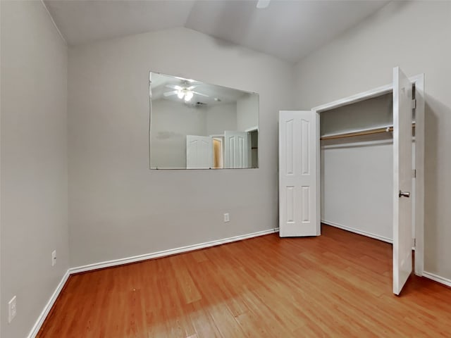 unfurnished bedroom featuring lofted ceiling, wood-type flooring, a closet, and ceiling fan