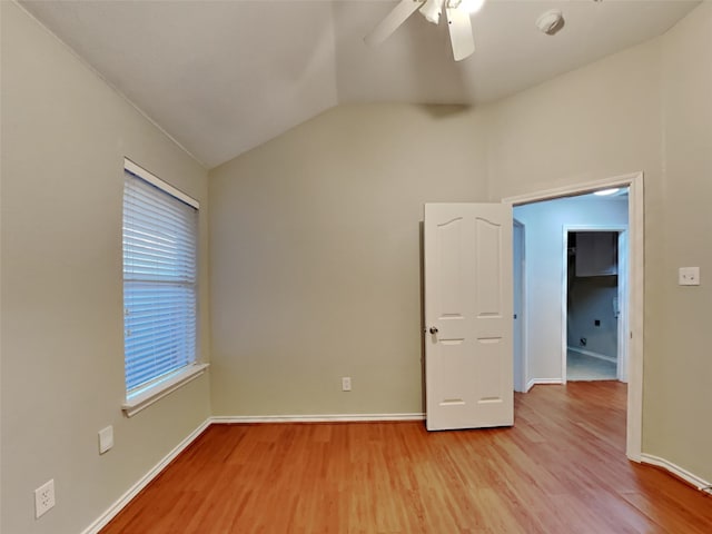 empty room with ceiling fan, vaulted ceiling, and light wood-type flooring