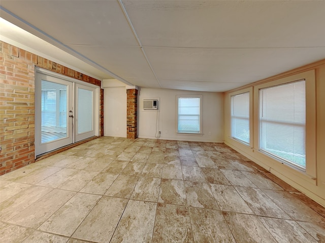 empty room featuring an AC wall unit and brick wall