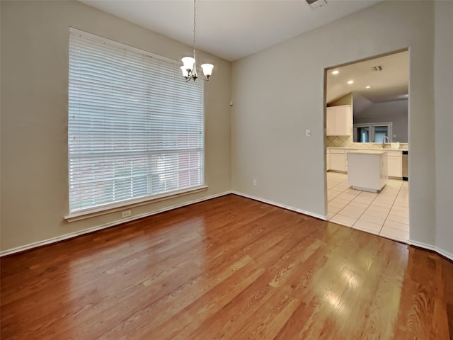 unfurnished dining area with light hardwood / wood-style floors and a notable chandelier