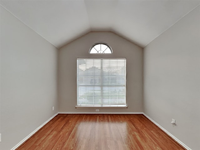 empty room with vaulted ceiling and light hardwood / wood-style floors