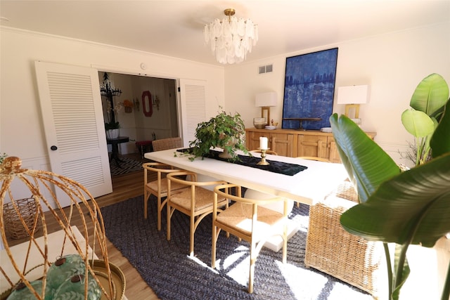 dining space featuring hardwood / wood-style flooring, crown molding, and an inviting chandelier