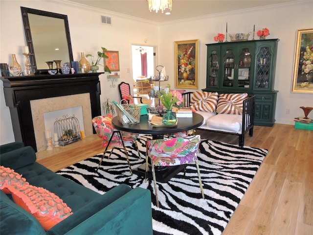 living room with ornamental molding, an inviting chandelier, and light hardwood / wood-style flooring