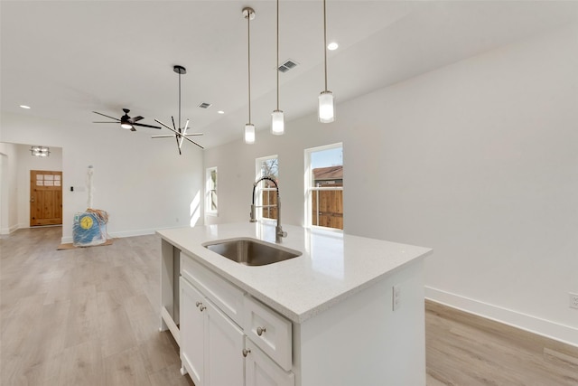 kitchen featuring white cabinets, sink, a kitchen island with sink, and light wood-type flooring