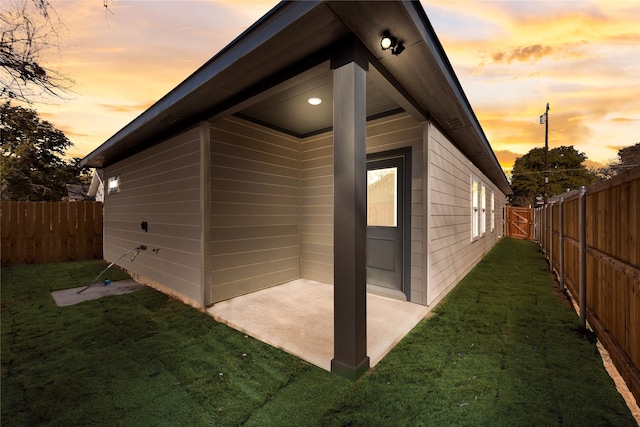 property exterior at dusk featuring a patio area and a lawn