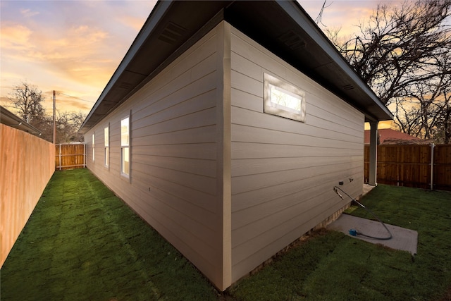 property exterior at dusk featuring a lawn