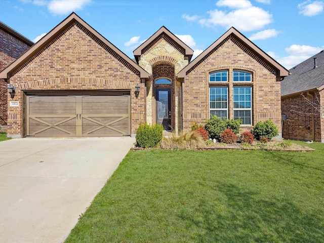 french provincial home with concrete driveway, an attached garage, brick siding, and a front yard