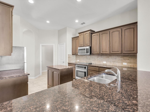 14824 Angel Trace Dr, Aledo, TX 76008 - kitchen with a sink, backsplash, stainless steel appliances, arched walkways, and dark stone counters