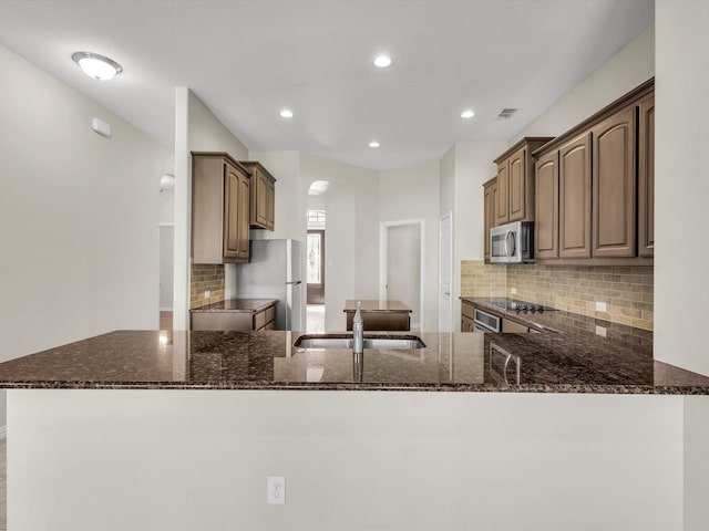 14824 Angel Trace Dr, Aledo, TX 76008 - kitchen featuring a sink, stainless steel microwave, freestanding refrigerator, dark stone counters, and arched walkways