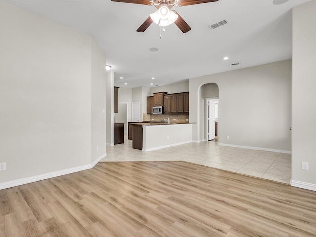 14824 Angel Trace Dr, Aledo, TX 76008 - unfurnished living room featuring a ceiling fan, baseboards, visible vents, arched walkways, and light wood-type flooring