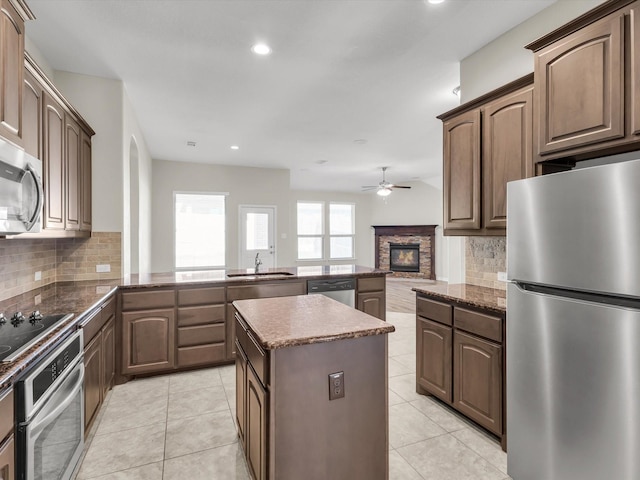 14824 Angel Trace Dr, Aledo, TX 76008 - kitchen with a stone fireplace, dark stone counters, stainless steel appliances, and a ceiling fan