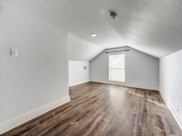 311 W Acheson St, Denison, TX 75020 - bonus room with hardwood / wood-style flooring, lofted ceiling, and a textured ceiling