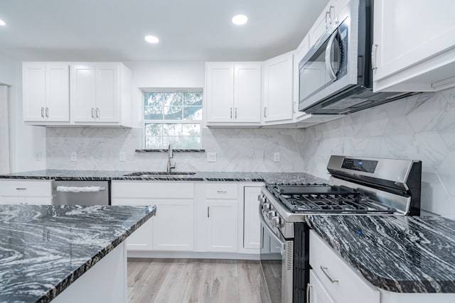 kitchen featuring white cabinetry, sink, dark stone countertops, backsplash, and stainless steel appliances