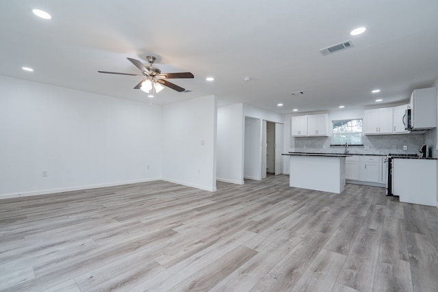 kitchen with ceiling fan, white cabinetry, tasteful backsplash, range with gas cooktop, and light wood-type flooring
