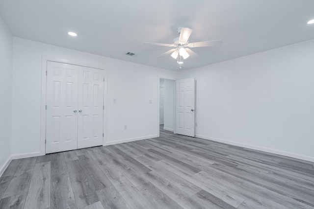 unfurnished bedroom with ceiling fan, light wood-type flooring, and a closet