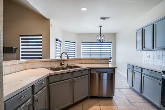 kitchen featuring sink, backsplash, hanging light fixtures, stainless steel dishwasher, and light tile patterned floors