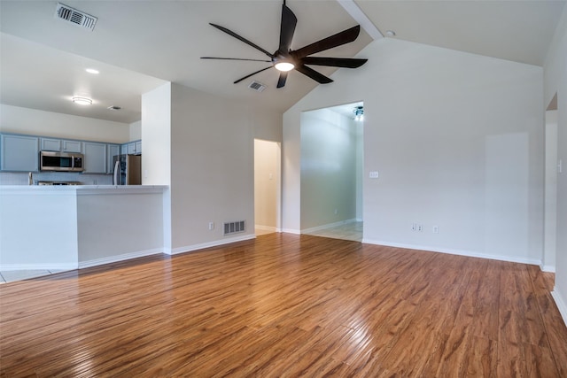 unfurnished living room with ceiling fan, beam ceiling, high vaulted ceiling, and light hardwood / wood-style flooring