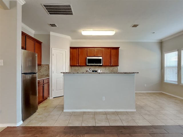 kitchen featuring tasteful backsplash, appliances with stainless steel finishes, crown molding, and a center island with sink