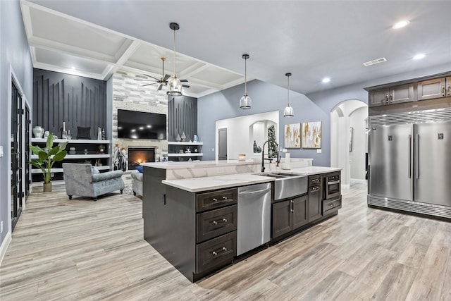 kitchen with stainless steel appliances, hanging light fixtures, sink, and dark brown cabinetry