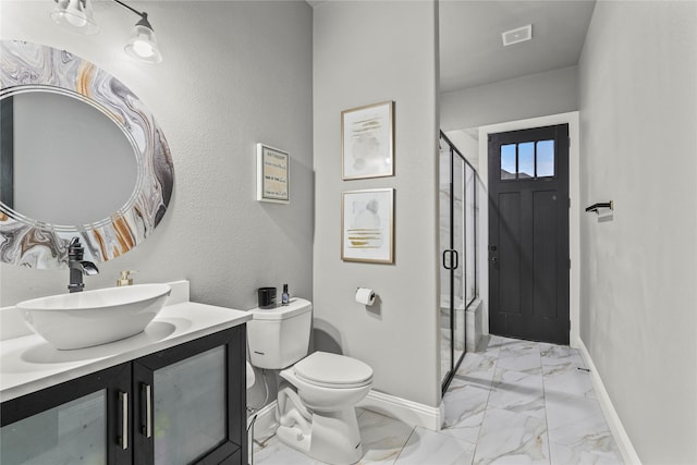 bathroom with vanity, a shower with door, and toilet