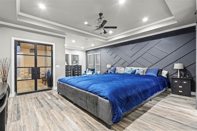 bedroom with crown molding, a raised ceiling, and light wood-type flooring