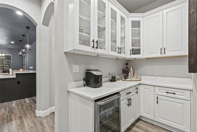 bar with white cabinets, pendant lighting, beverage cooler, and light hardwood / wood-style flooring