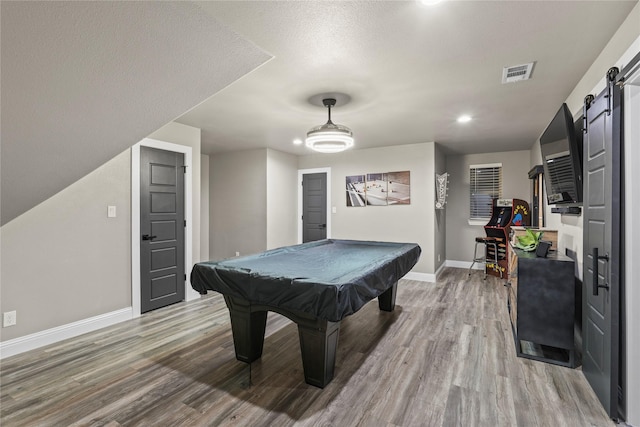 rec room featuring hardwood / wood-style flooring, billiards, a barn door, and a textured ceiling