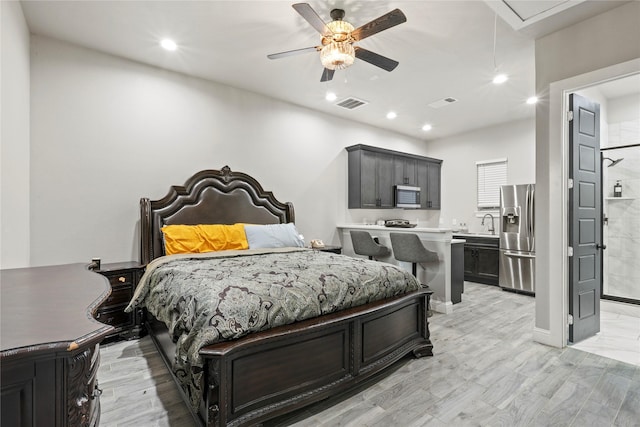 bedroom with connected bathroom, sink, light wood-type flooring, stainless steel fridge, and ceiling fan