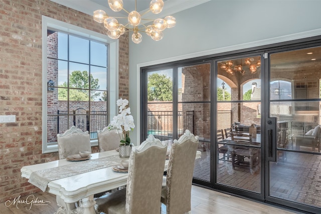 dining area featuring brick wall, a chandelier, and light wood-type flooring