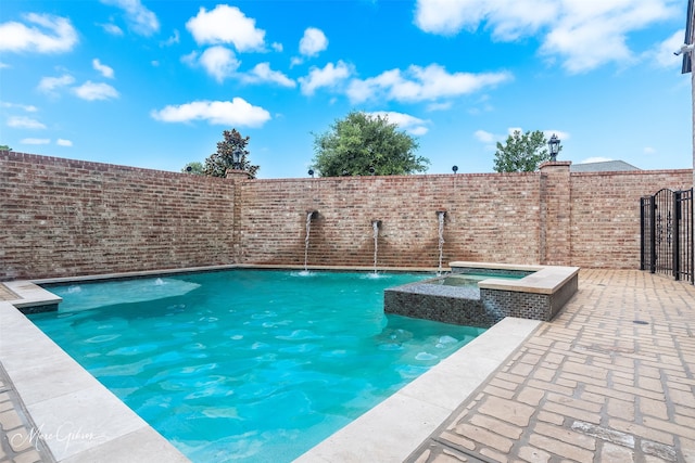 view of swimming pool featuring a patio area, pool water feature, and an in ground hot tub