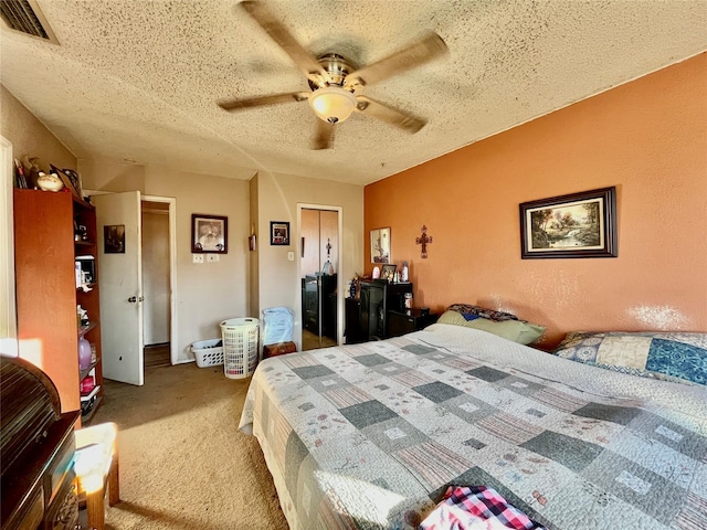 bedroom with ceiling fan, carpet floors, and a textured ceiling