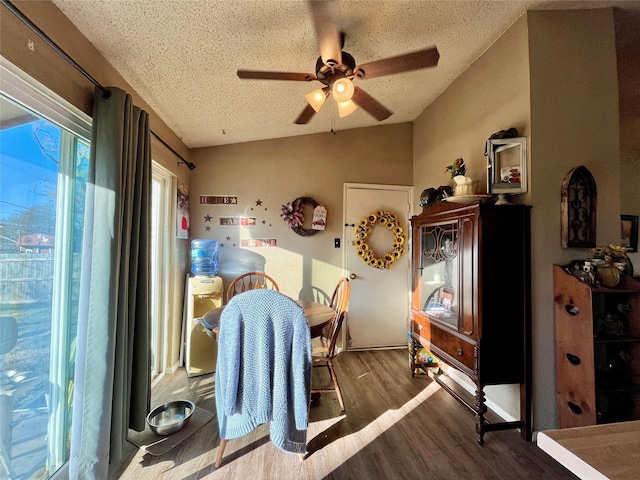 dining space with ceiling fan, wood-type flooring, vaulted ceiling, and a textured ceiling