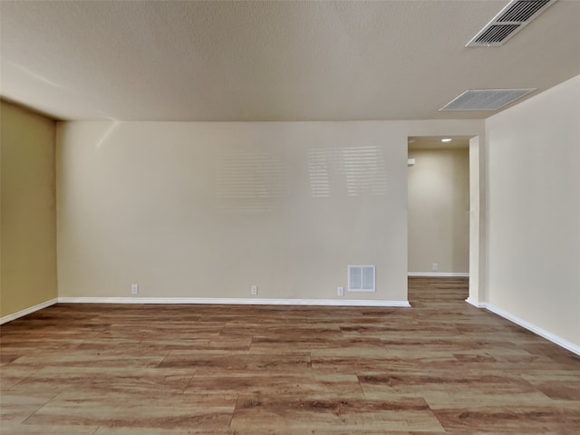 spare room featuring a textured ceiling and light hardwood / wood-style flooring