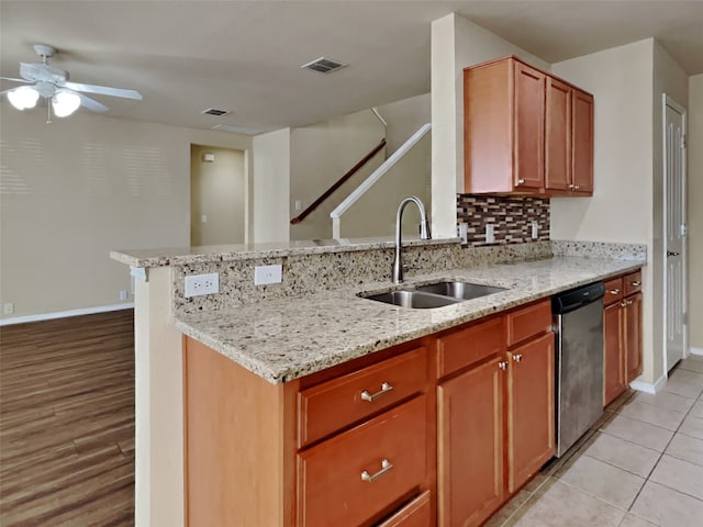 kitchen with sink, light stone countertops, decorative backsplash, stainless steel dishwasher, and kitchen peninsula