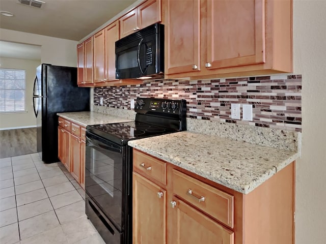 kitchen featuring light tile patterned flooring, light stone countertops, decorative backsplash, and black appliances