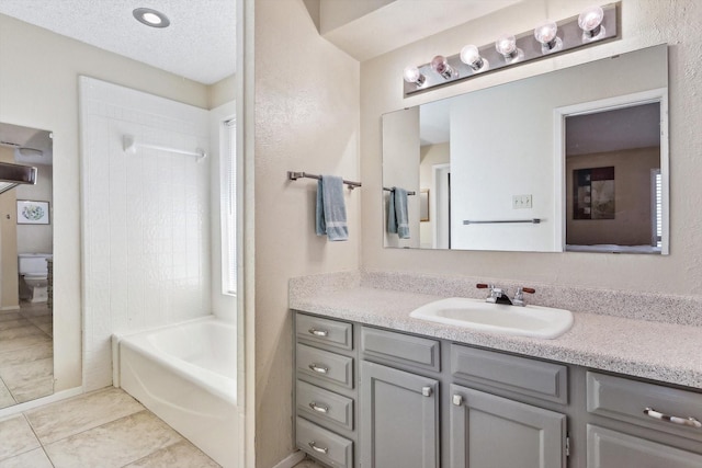 full bathroom with tiled shower / bath combo, vanity, a textured ceiling, tile patterned floors, and toilet