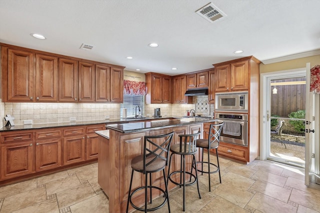 kitchen featuring a breakfast bar, stainless steel appliances, a center island, and backsplash