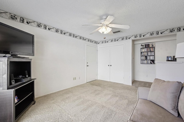 carpeted living room with ceiling fan and a textured ceiling