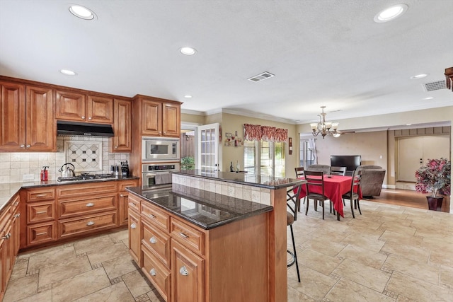 kitchen featuring a center island, appliances with stainless steel finishes, a kitchen breakfast bar, pendant lighting, and decorative backsplash