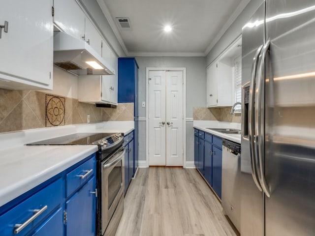 kitchen featuring sink, white cabinets, ornamental molding, stainless steel appliances, and blue cabinetry