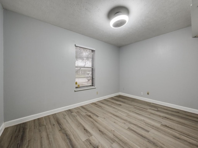 spare room with a textured ceiling and light hardwood / wood-style floors