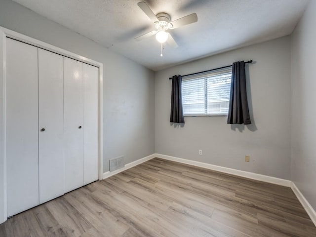 unfurnished bedroom with light hardwood / wood-style floors, a closet, and ceiling fan