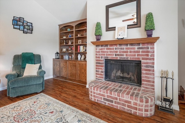 living room featuring lofted ceiling, dark hardwood / wood-style flooring, and a brick fireplace